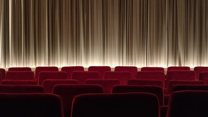 Teater & Nöjen Teatersalong med röda stolsrader framför scenen.